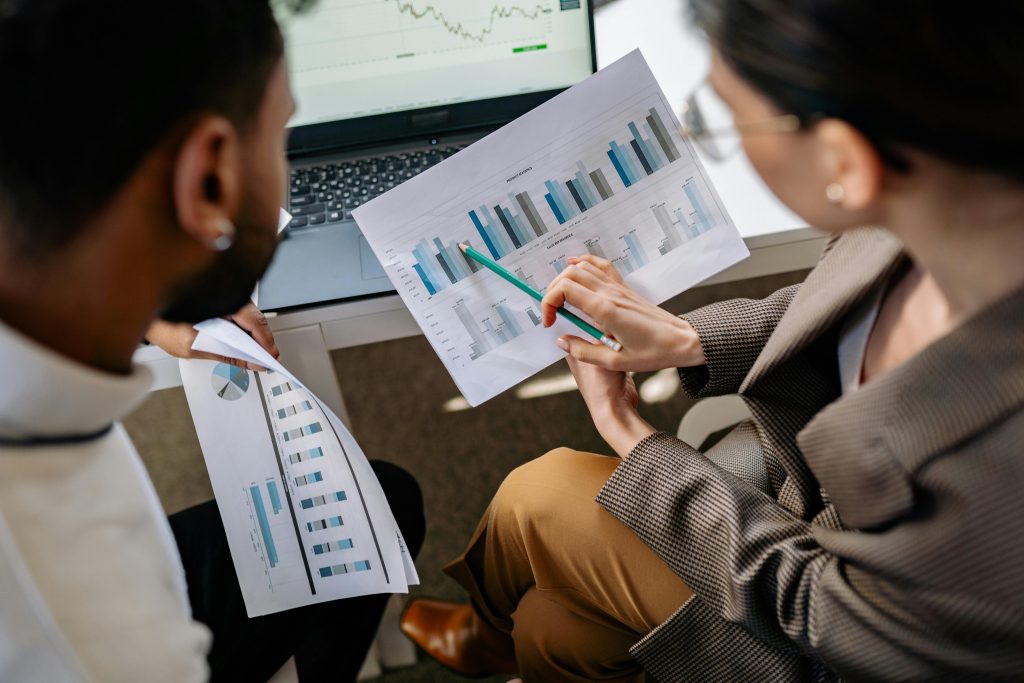 two person discussing graphs on printouts